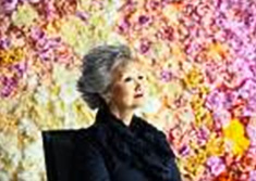 Adrienne Clarkson assise devant un mur de fleurs 