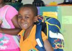 Un jeune garon tout souriant, son sac  dos rempli d'articles scolaires 