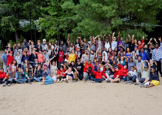 Un grand groupe de jeunes sur la plage salue de la main
